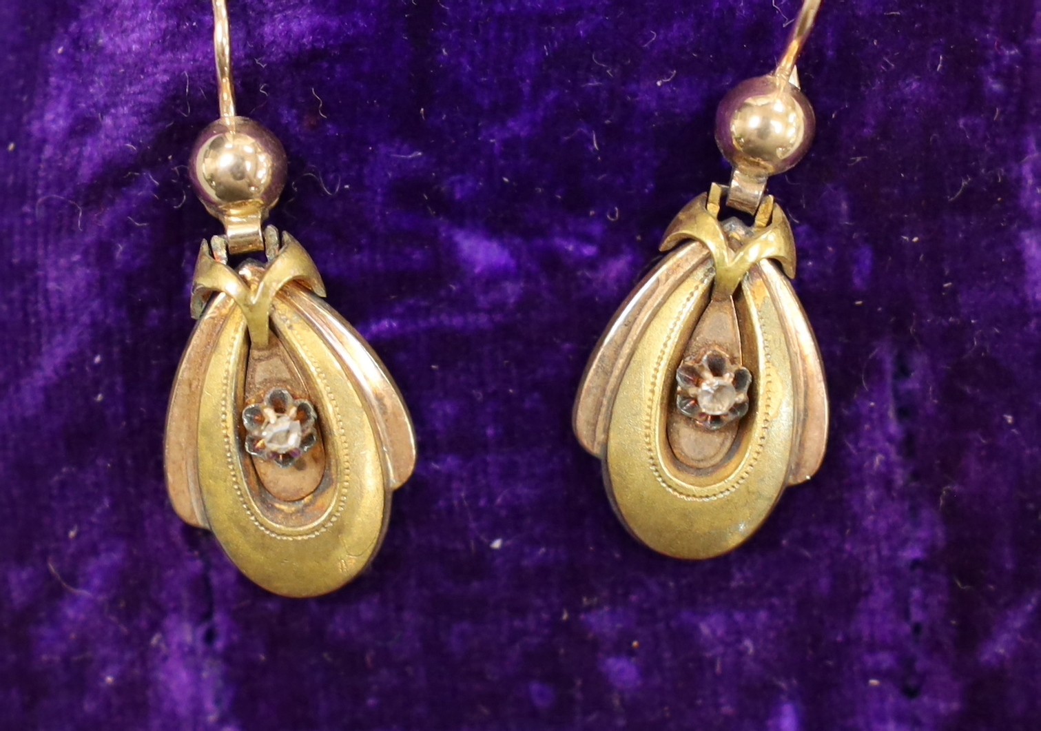 A Victorian 15ct two colour gold and diamond set pendant brooch, of oval form with central stylised motif, 3.5cm, in fitted case with a pair of matching earrings, gross 10.2 grams